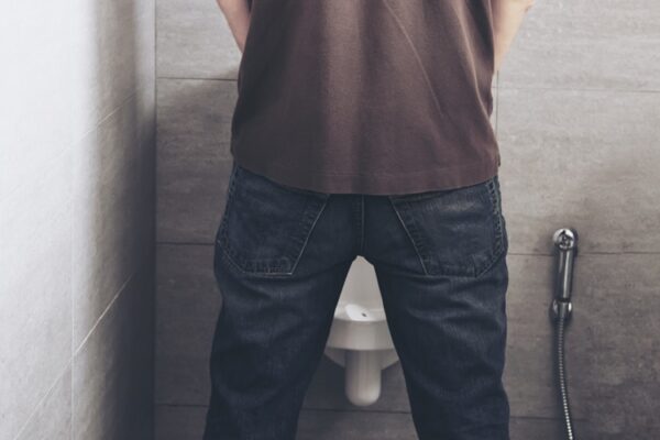 Man is standing pee in a toilet - healthcare urinal concept